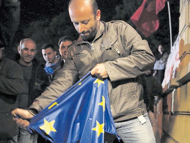 A protester rips an EU flag during an antibailout rally outside the presidential palace in Nicosia yesterday
