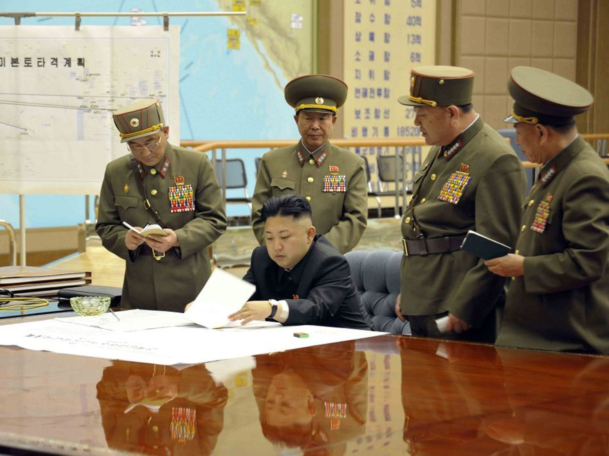 A picture released by the North Korean Central News Agency (KCNA) on 29 March 2013 shows North Korean leader Kim Jong-un (sitting) convening an urgent operation meeting