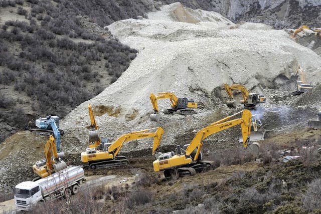 Earthmovers remove rocks and mud on the scene where the landslide hit