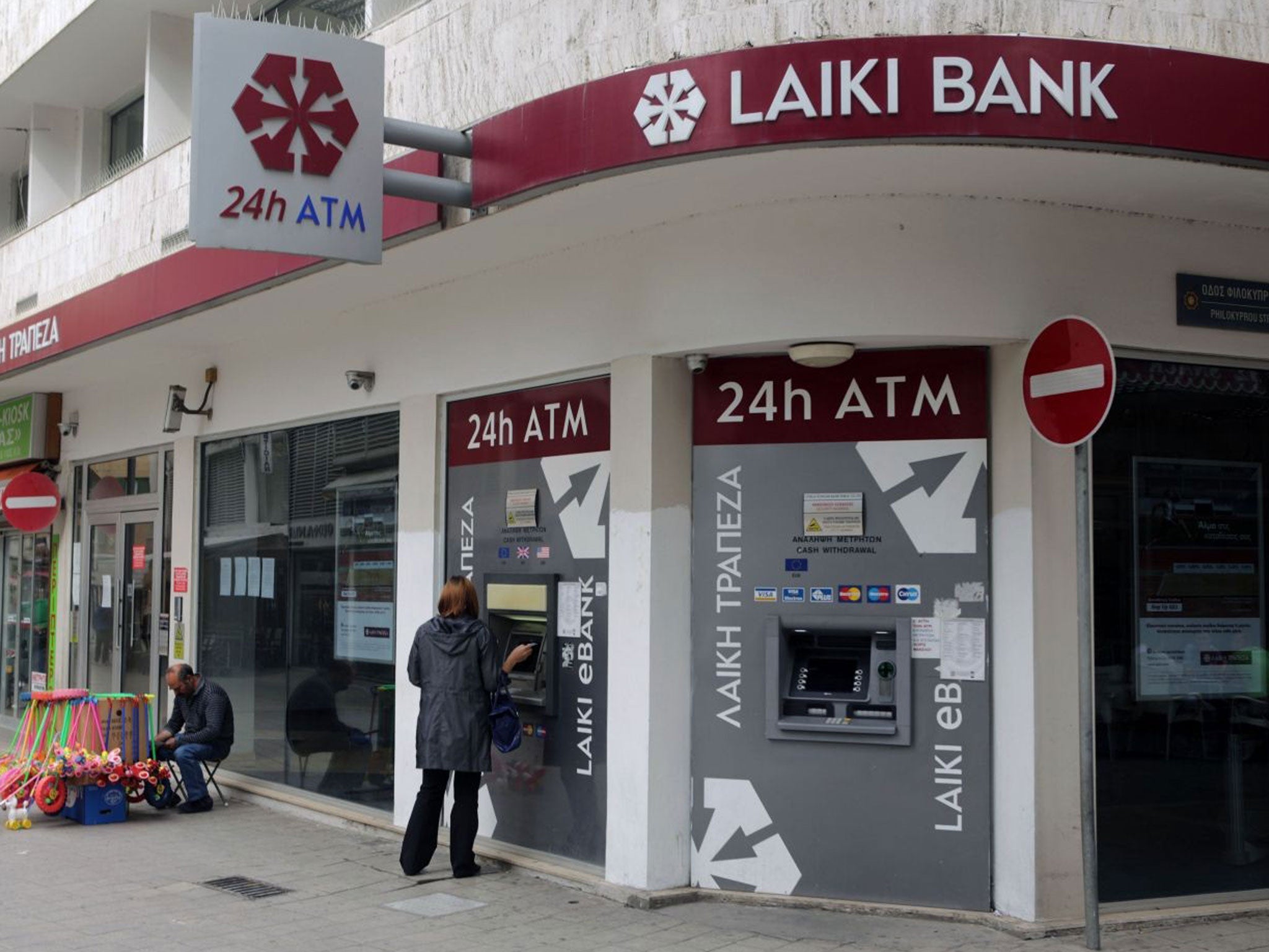 A woman withdraws money from the ATM of a Laiki bank branch