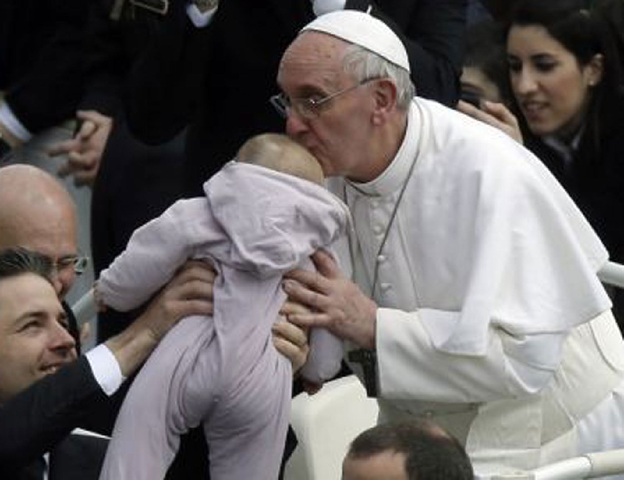 Pope Francis kisses a baby after his first Easter Sunday message