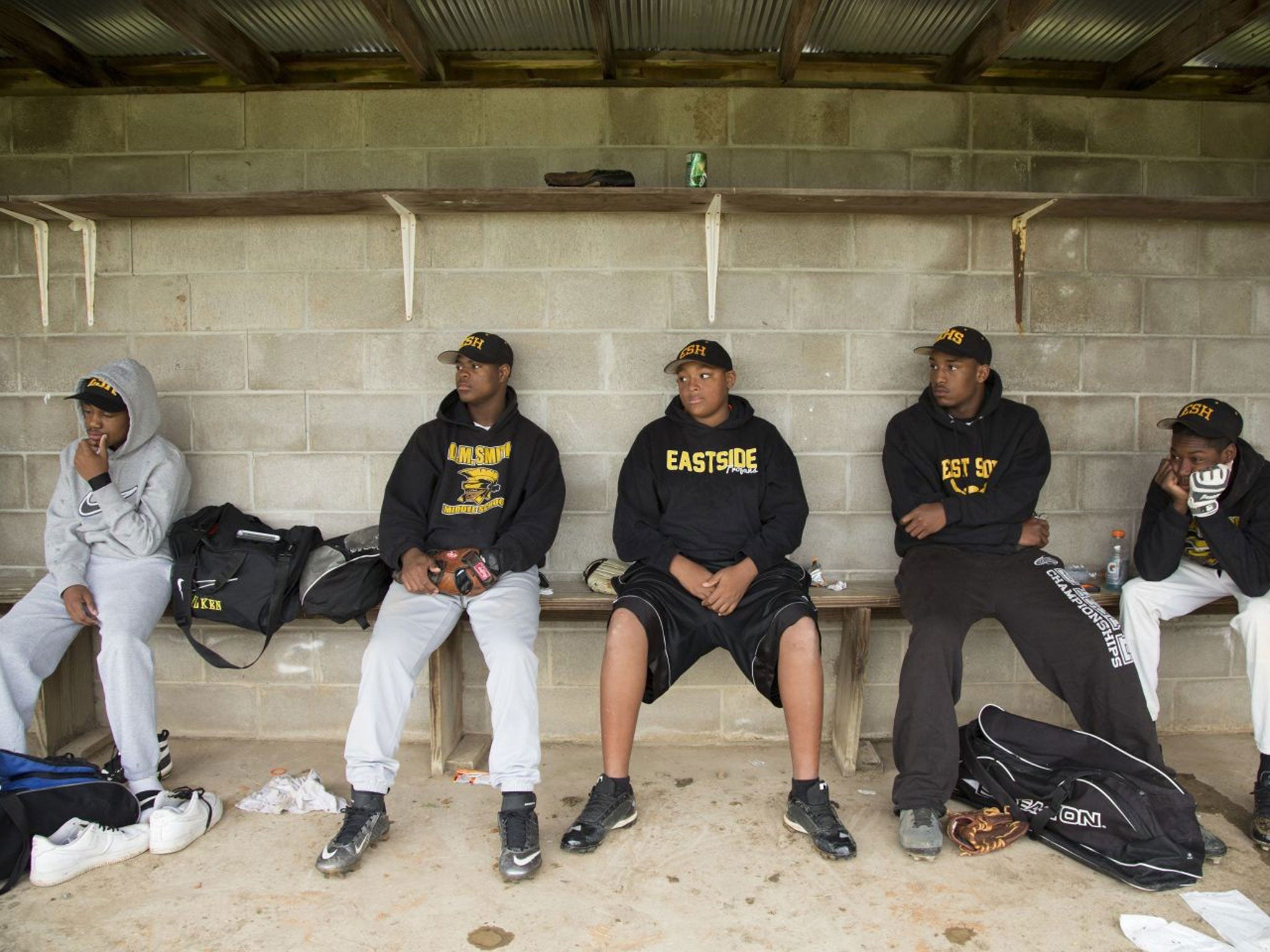 Members of the Cleveland's East Side High School baseball team listen to a pep talk from head coach Herman Cox