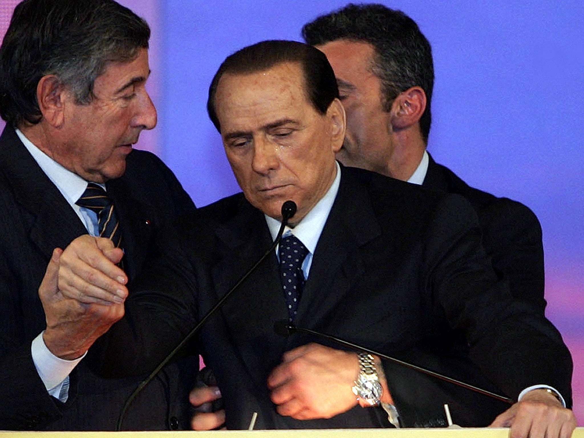 Former Italian premier Silvio Berlusconi, centre, is supported at the podium by his personal doctor Umberto Scapagnini, left