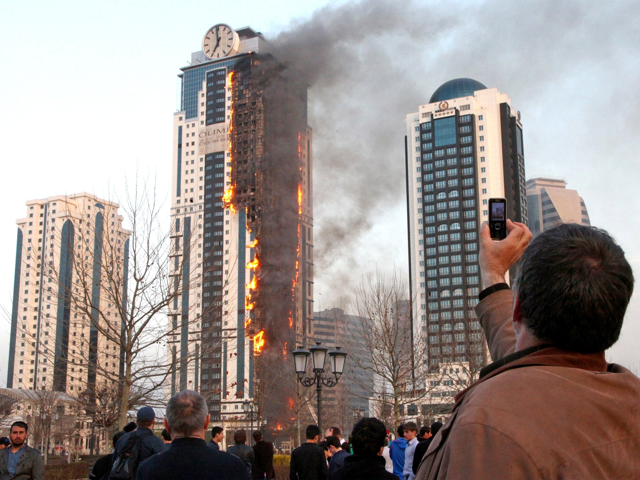 A man takes a picture of a burning skyscraper in central Grozny, Chechnya, yesterday