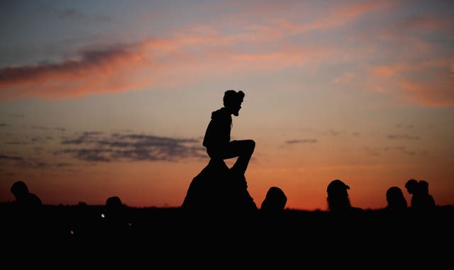 Glastonbury romance? Revellers watch the sunrise from the stone circle during the festival