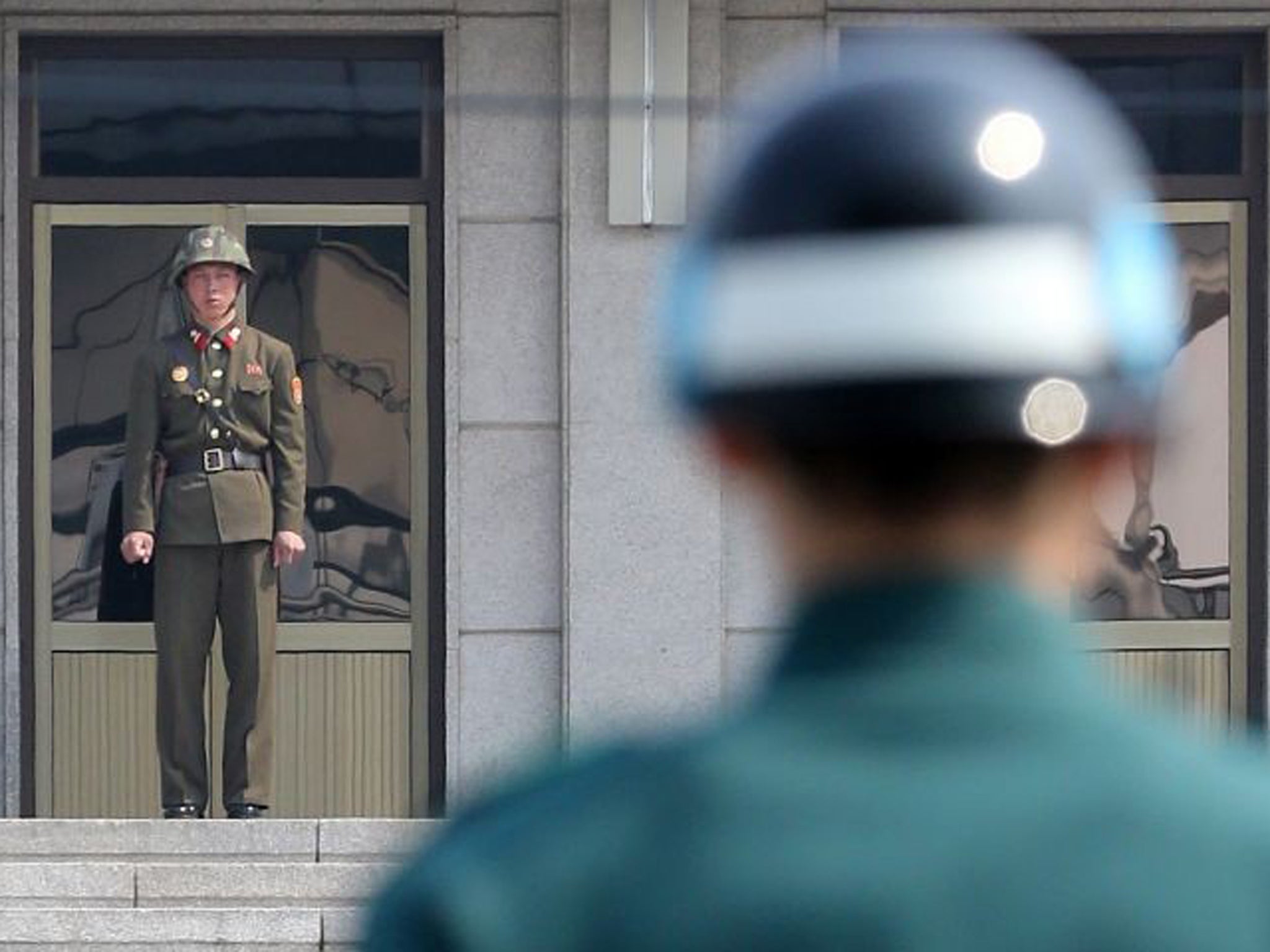 Soldiers from South Korea (R) and North Korea (C) stand guard on their respective sides at the truce village of Panmunjom in the demilitarized zone