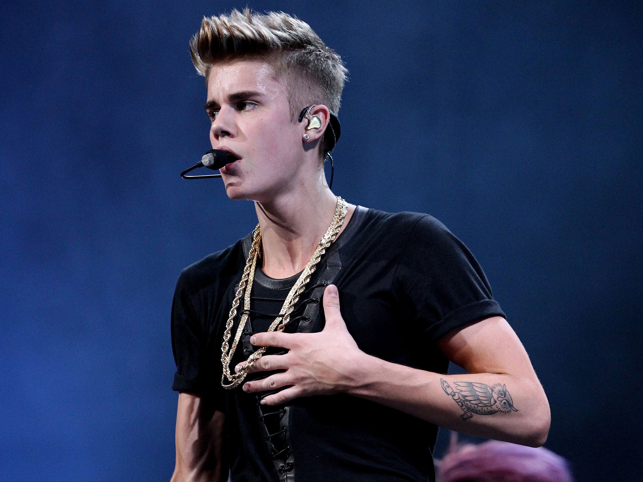 Justin Bieber shows off one of his tattoos onstage during KISS FM's 2012 Jingle Ball