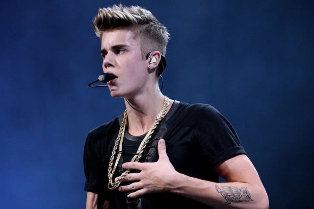 Justin Bieber shows off one of his tattoos onstage during KISS FM's 2012 Jingle Ball