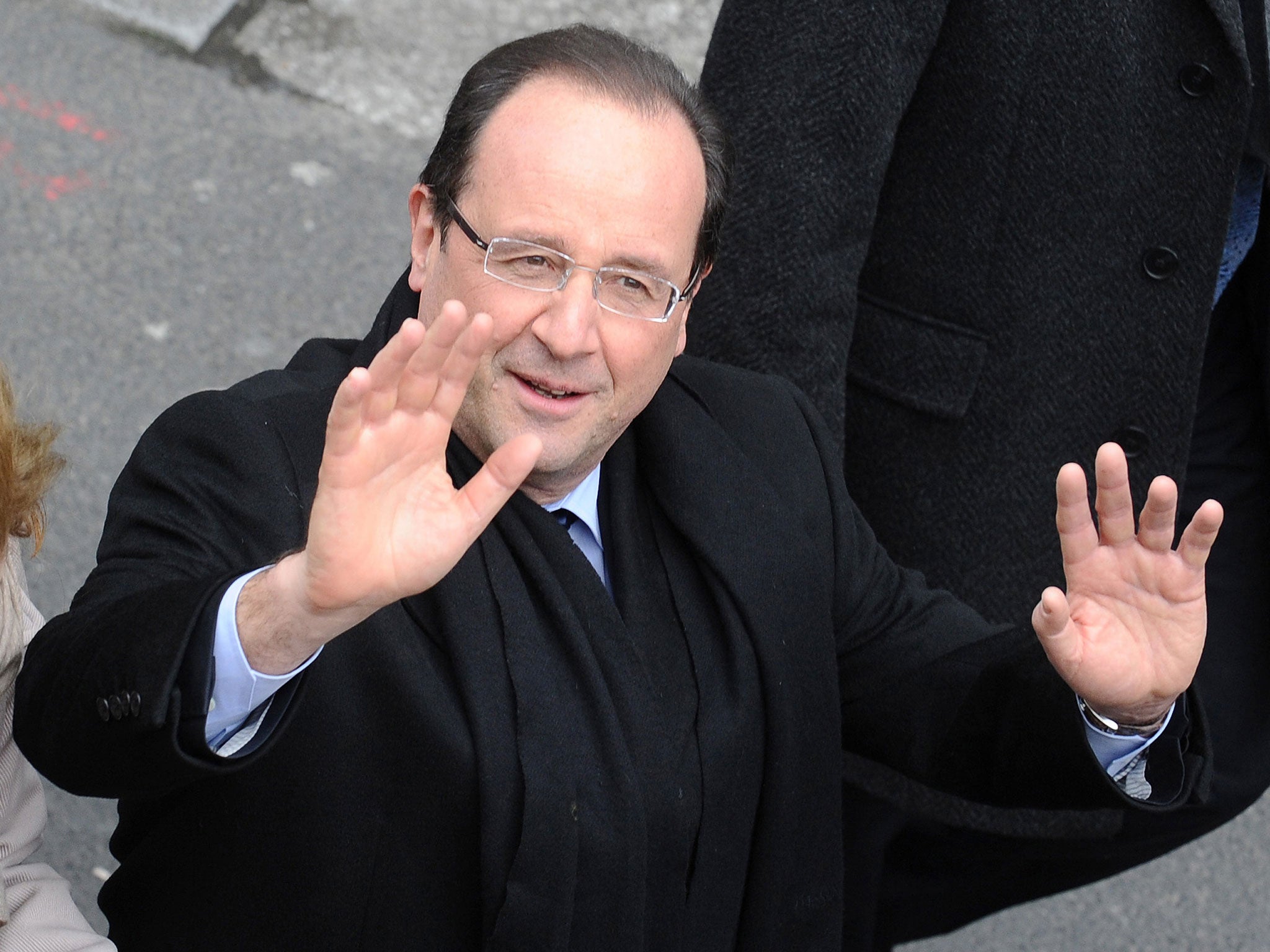 French President Francois Hollande waves as he walks in a street in Tulle, southern France, on April 6, 2013.