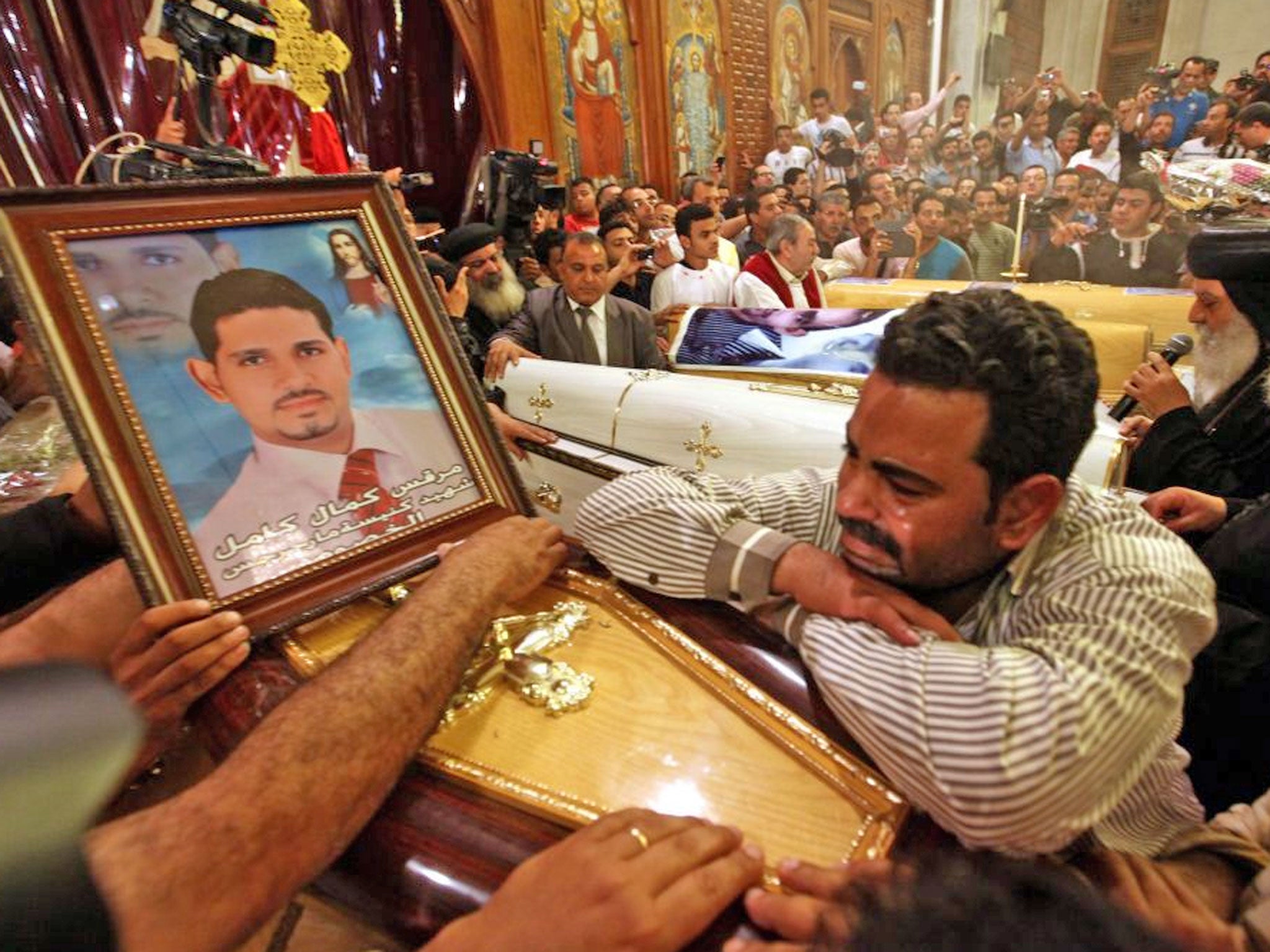 An Egyptian Coptic Christian mourns over the coffin of a relative killed in clashes yesterday, during the funeral mass at the Abbassiya Cathedral, in Cairo today