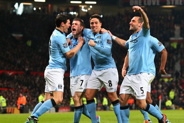 James Milner celebrates with his City team-mates after scoring against United