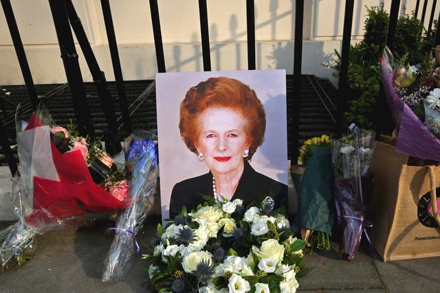 A portrait of former Prime Minister Margaret Thatcher is left next to floral tributes outside her residence