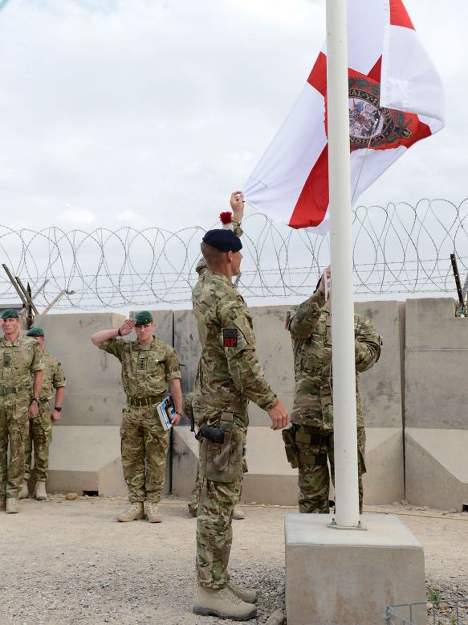 Troops from 40 Commando Royal Marines symbolically lowering the Royal Navy's white ensign that has flown above their main operating base in the Nahr-e Saraj district for over a decade
