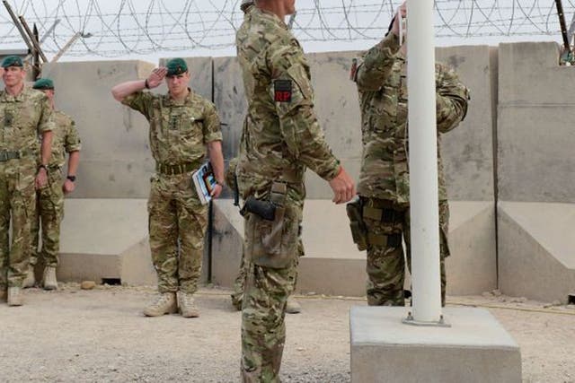 Troops from 40 Commando Royal Marines symbolically lowering the Royal Navy's white ensign that has flown above their main operating base  in the Nahr-e Saraj district for over a decade