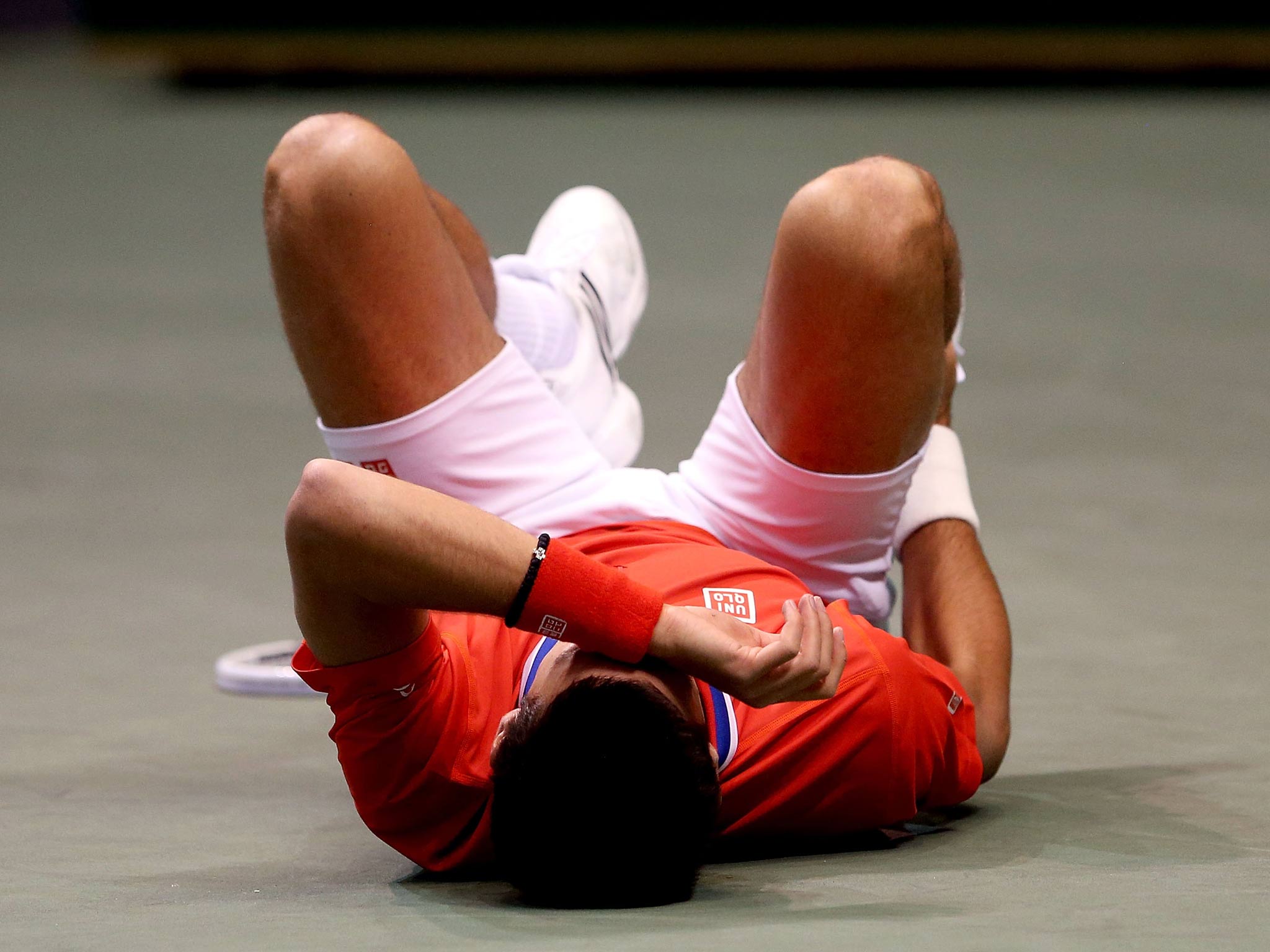 Novak Djokovic of Serbia falls to the court in pain after injuring his ankle on Davis Cup duty