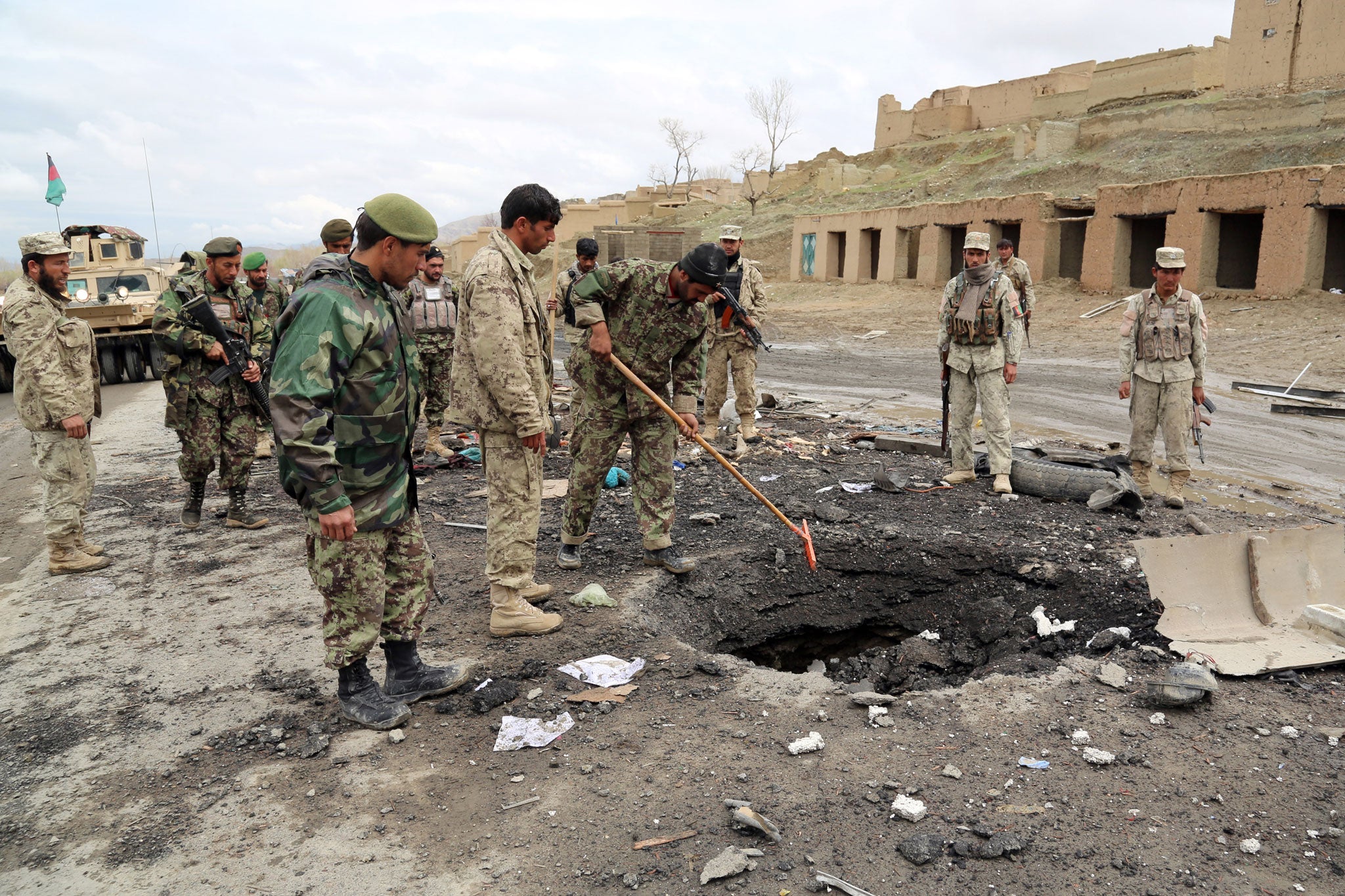 Afghanistan security forces investigate the site of a roadside bomb blast blamed on the Taliban