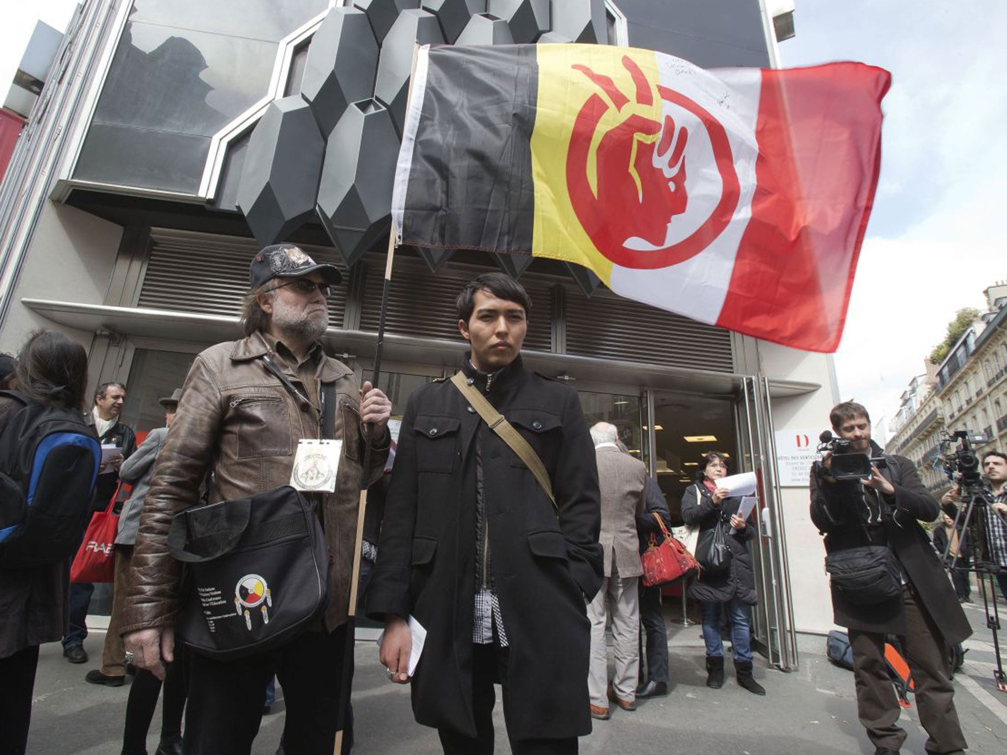 A French supporter of the Indian cause, who refused to give his name, left, holds a flag of the American Indian Movement and an American exchange student, member of the Arizona's Hopi tribe, Bo Lomahquahu, right, stand outside of the Druout's auction hous