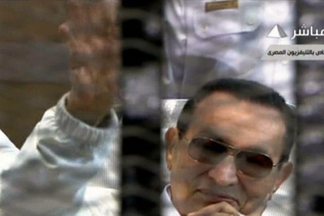 An image grab taken from Egyptian state TV shows ousted Egyptian president Hosni Mubarak waving from behind bars during his retrial at the Police Academy in Cairo