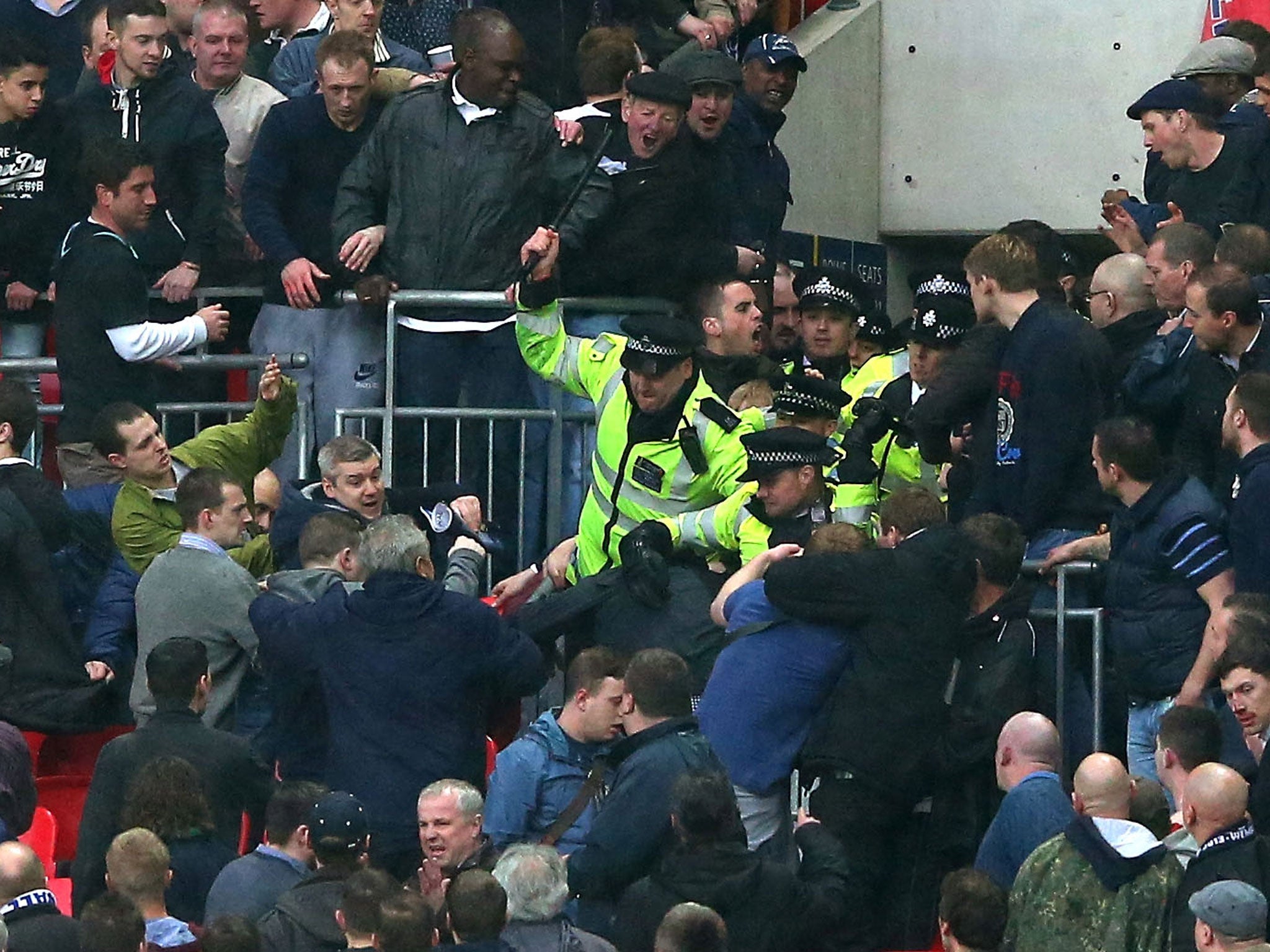 Police officers wield batons as they attempt to stop Millwall supporters fighting amongst themselves