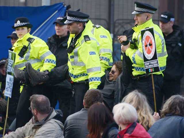 An anti-Trident demonstrator is taken away by police during a blockade at one of the entrances to Faslane naval base