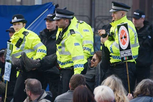 An anti-Trident demonstrator is taken away by police during a blockade at one of the entrances to Faslane naval base