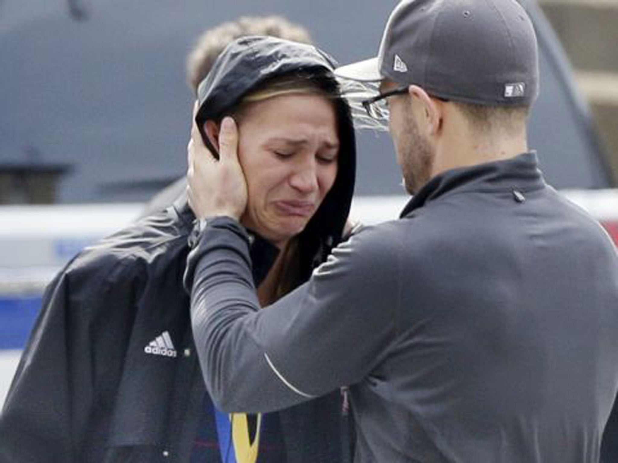 An unidentified Boston Marathon runner is comforted as she cries in the aftermath of two blasts which exploded near the finish line of the Boston Marathon