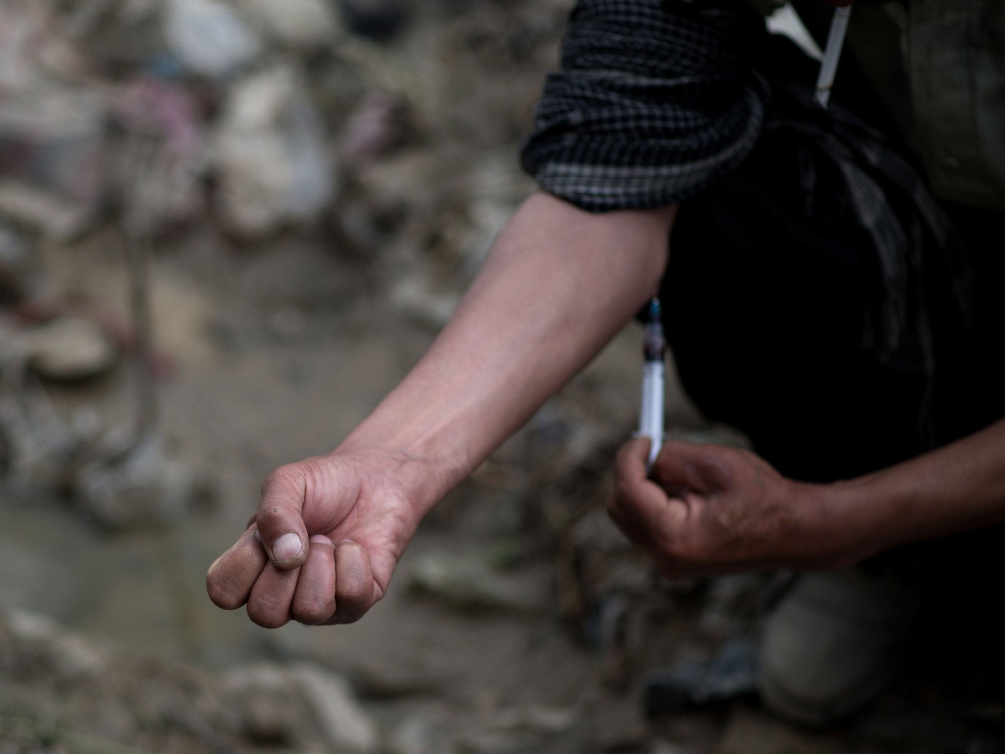 A drug addict injects heroin at a waste water canal in Kabul on April 25, 2012.
