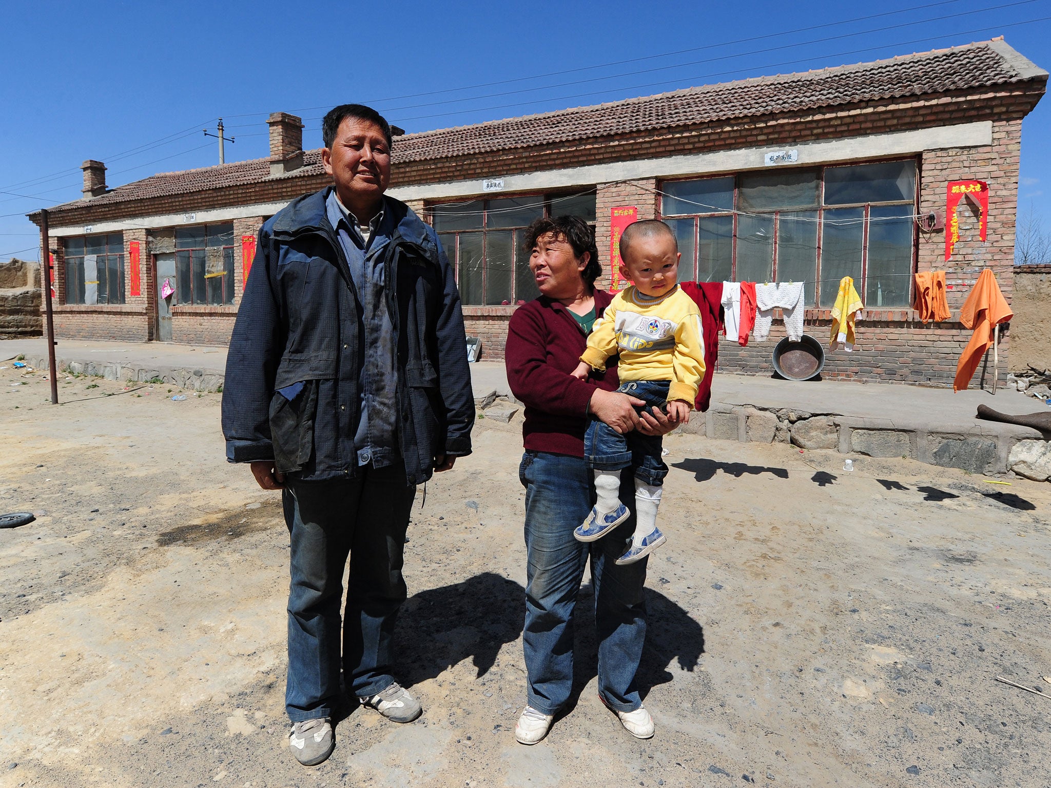 Peasant farmer Wang Tao, with his wife and grandson, outside his sparse home on April 21 , 2011near where he used to grow corn, potatoes and wheat within a stones's throw of a dumping ground for rare earths waste until toxic chemicals leaked into the water supply and poisoned his land near Baotou city in Inner Mongolia, northwest China. Farmers living near the tailings dam, a 10-square-kilometre expanse of toxic waste, say they have lost teeth and their hair has turned white while tests show the soil and water contain high levels of cancer-causing radioactive materials.