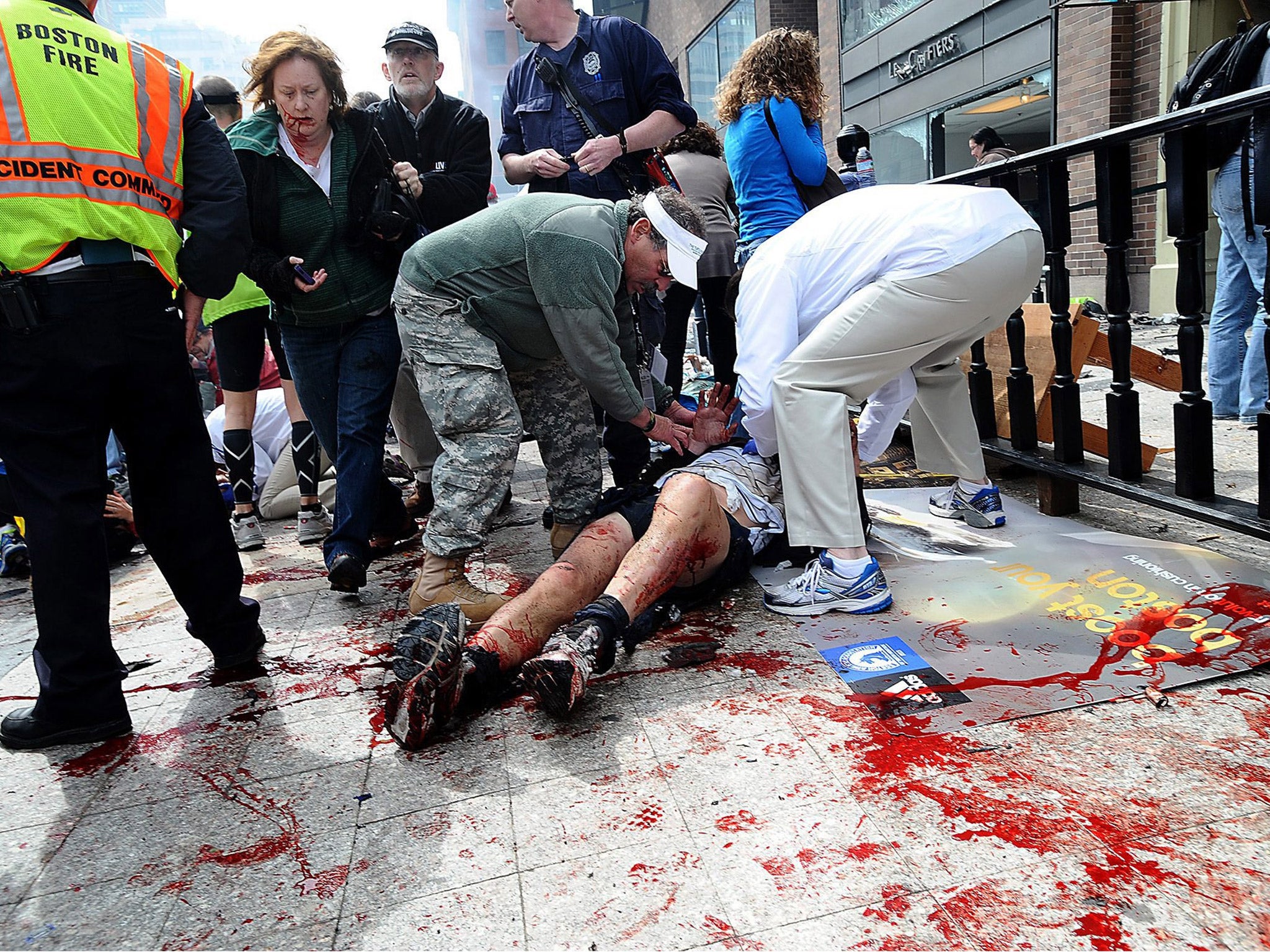 Bystanders tend to people injured by the explosions at the finishing line of the Boston Marathon on Monday