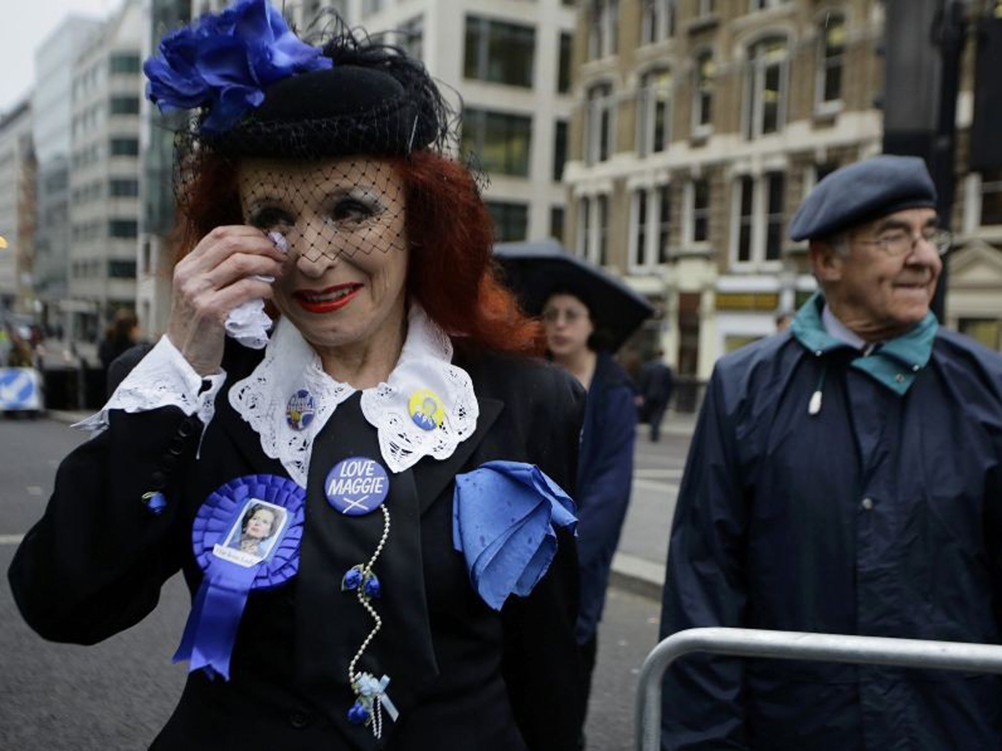 Gloria Martin, a supporter of former British prime minister Margaret Thatcher, wipes her tears as she joins others by the route of the funeral procession at St Paul's Cathedral