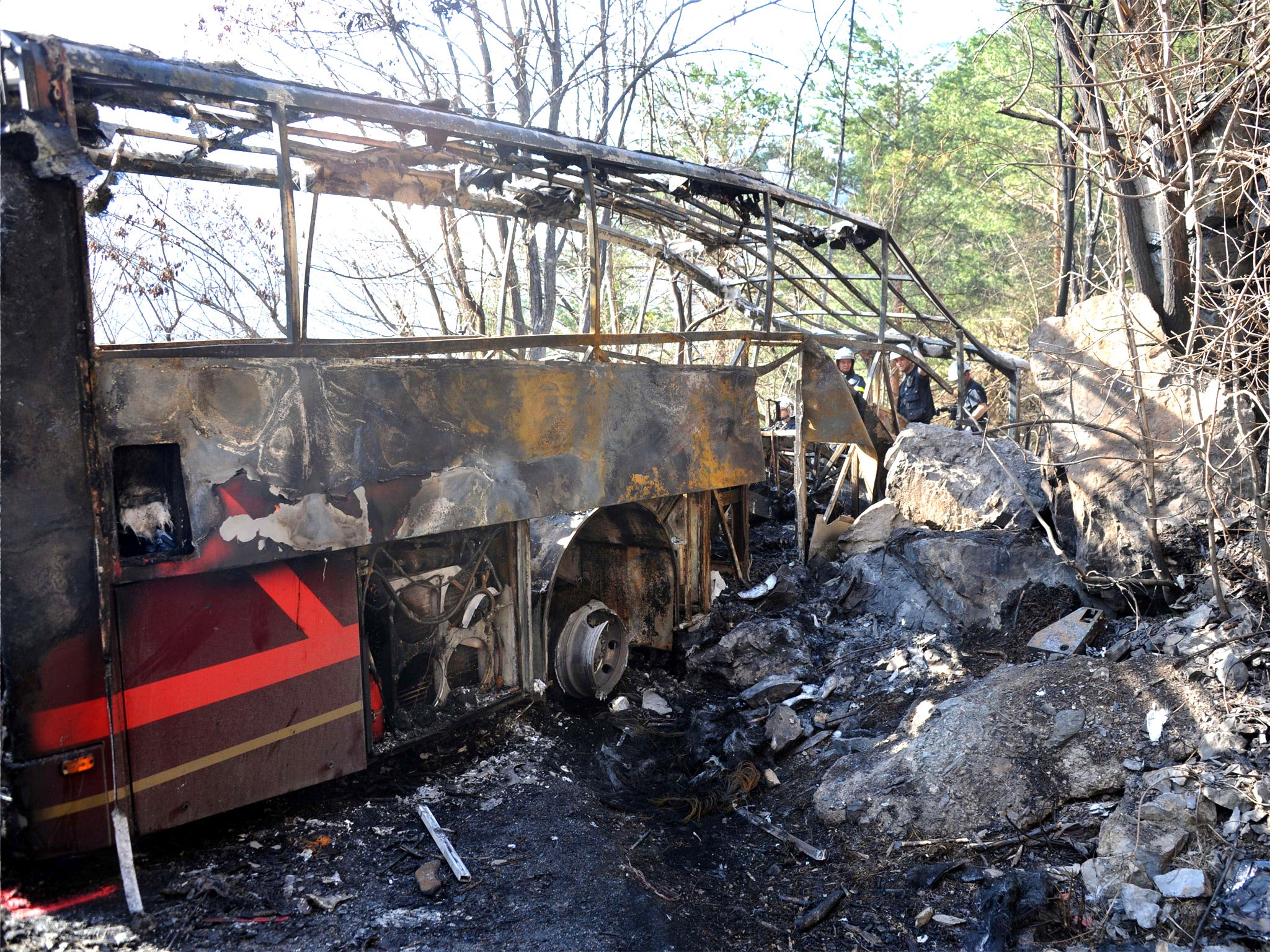 Firefighters stand by the wreckage of the coach