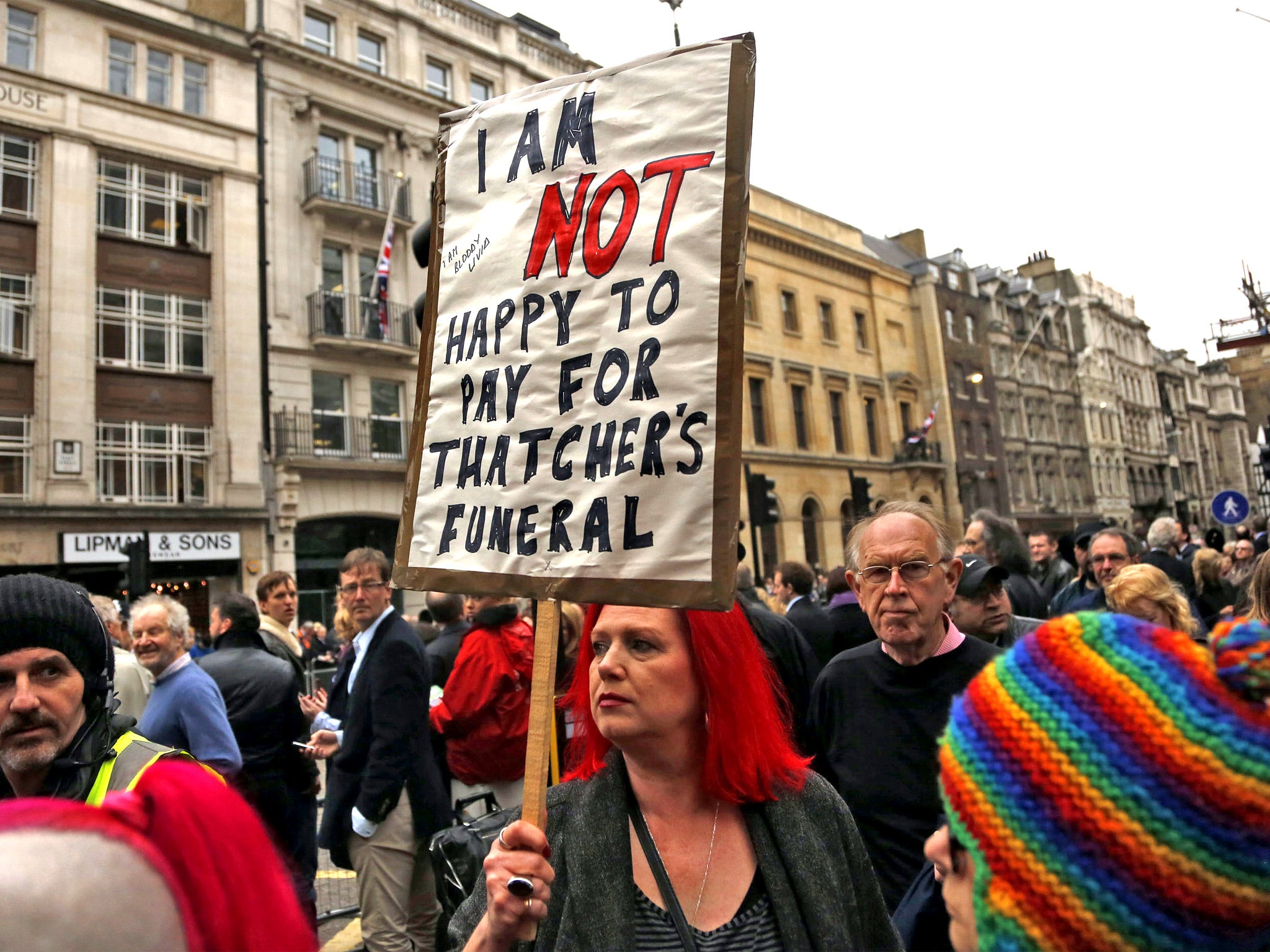 A demonstrator carries a protest sign during the funeral of former British prime minister Baroness Thatcher