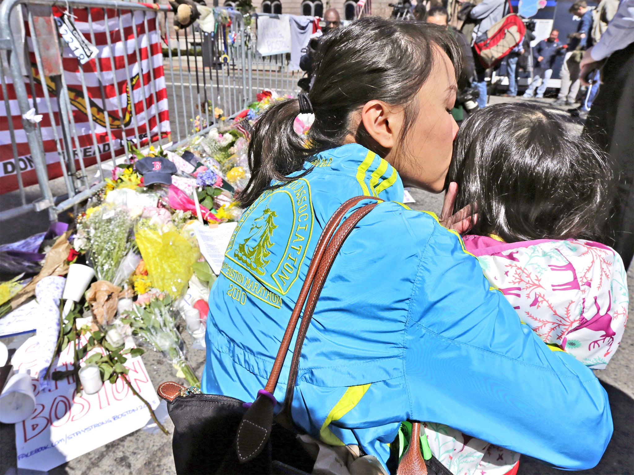 Marathon runner Vu Trang kisses her two-year-old daughter Cara at a memorial in Boylston Street