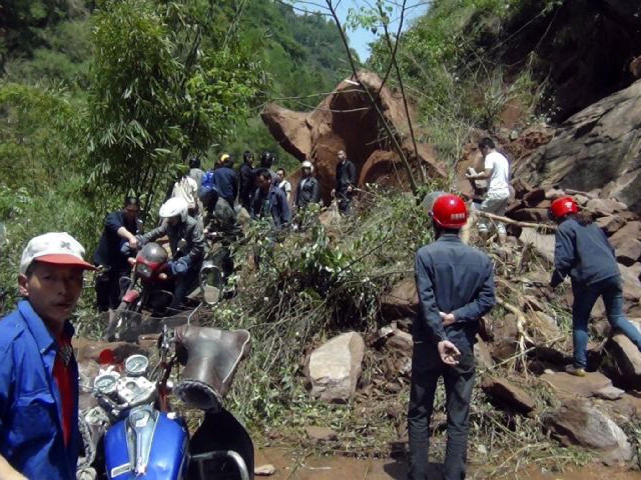 Rescuers try to remove rocks blocking a road after a strong earthquake of 6.6 magnitude hit Lushan county, Ya'an, Sichuan province