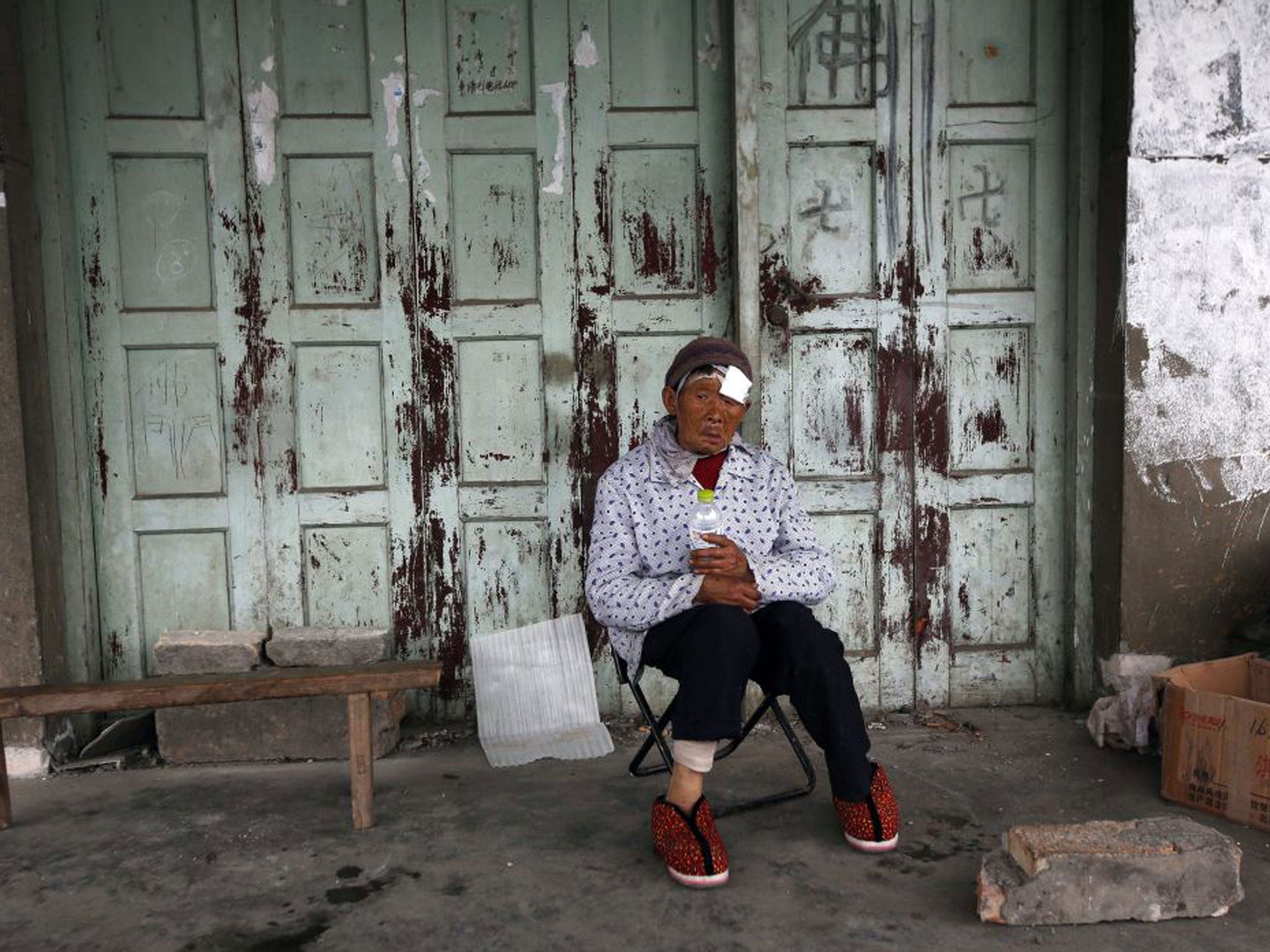 Resident Chen Biying sits in front of her house after being injured during the earthquake in Ya'an