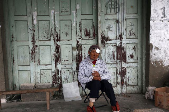 Resident Chen Biying sits in front of her house after being injured during the earthquake in Ya'an