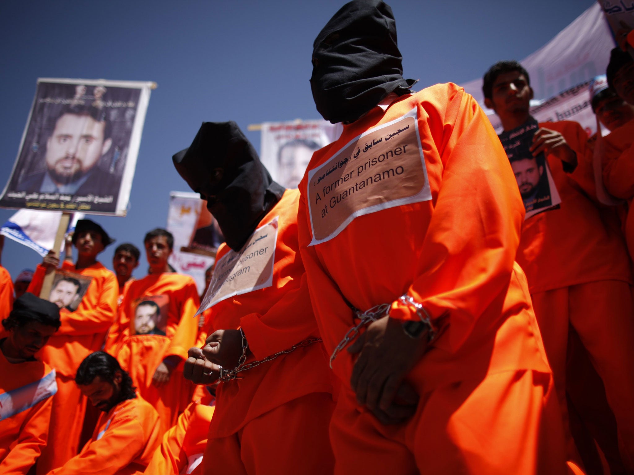 Former Guantanamo Bay detainees wear black hoods during a protest