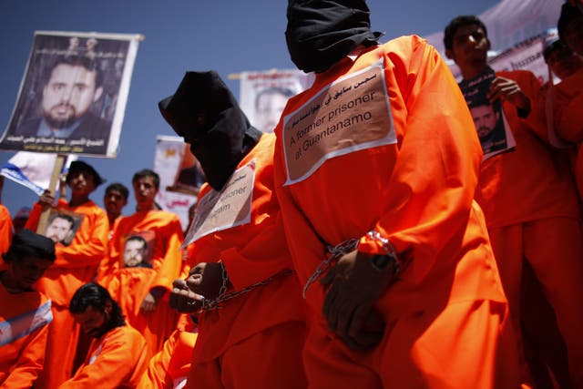 Former Guantanamo Bay detainees wear black hoods during a protest
