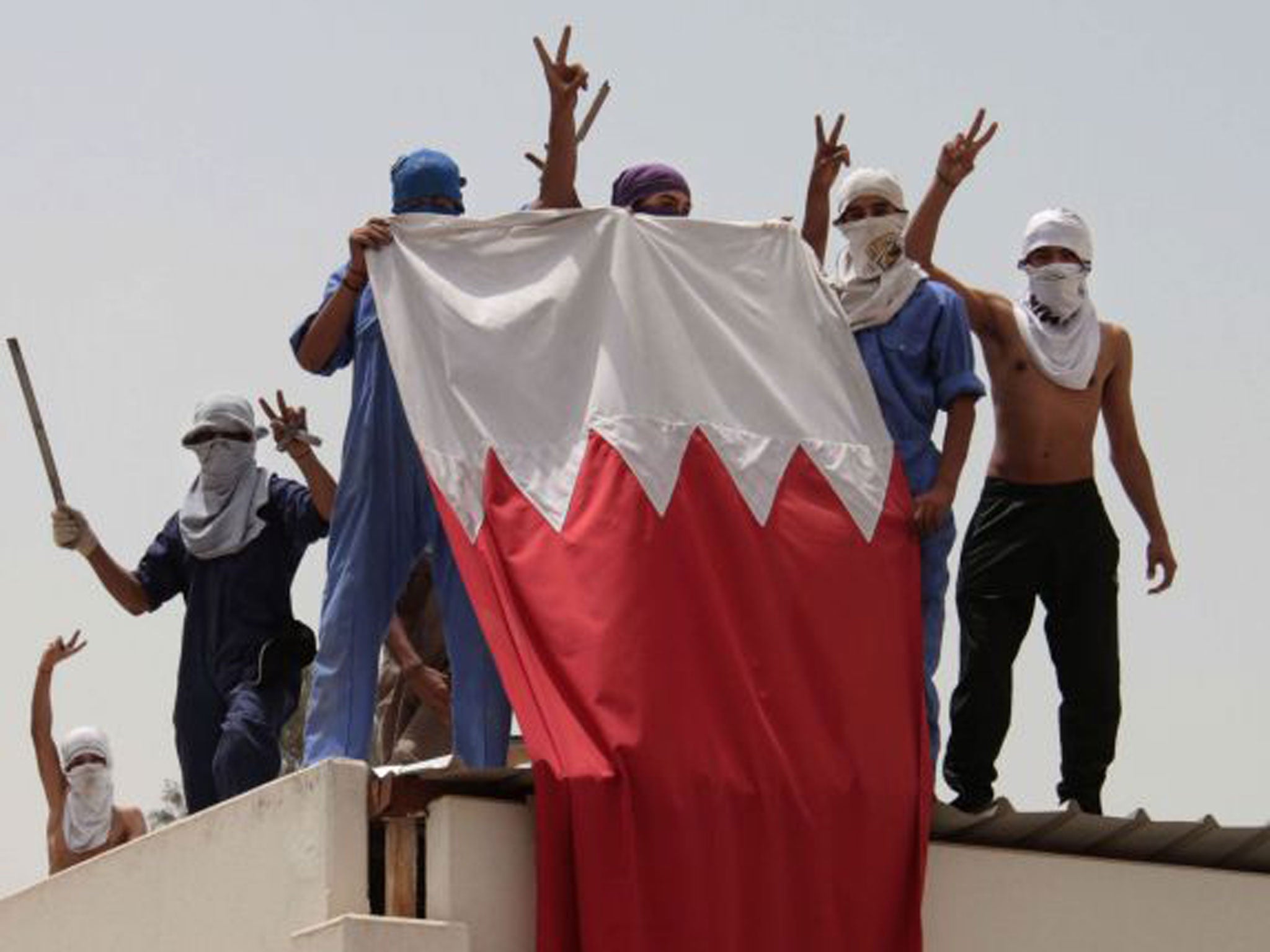 Bahraini students carry their national flag during clashes with riot police in Manama, Bahrain