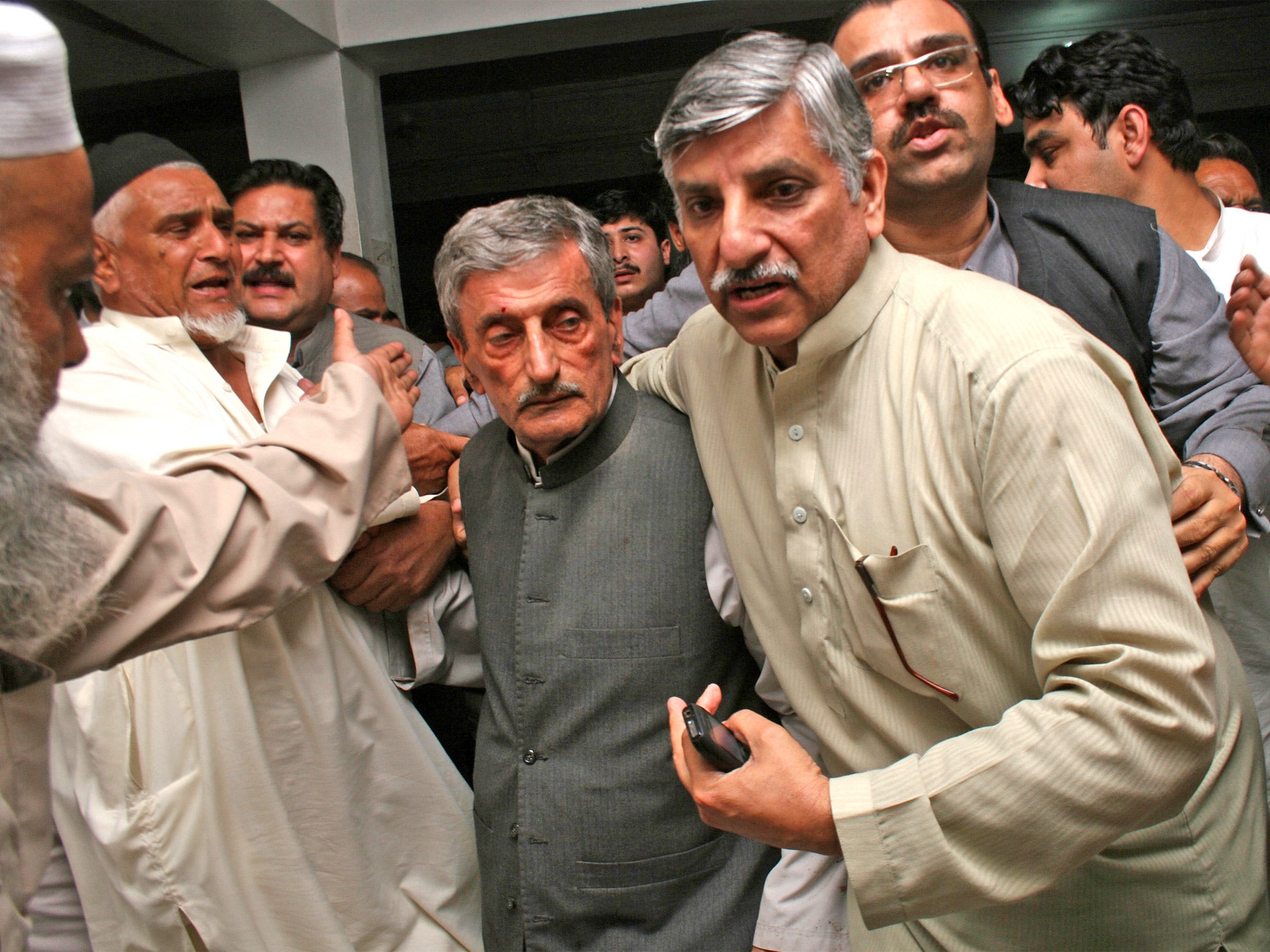 People escort a shocked Pakistani politician, Ghulam Ahmed Bilour, center, who survived a suicide attack, at a hospital in Peshawar