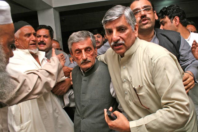 People escort a shocked Pakistani politician, Ghulam Ahmed Bilour, center, who survived a suicide attack, at a hospital in Peshawar