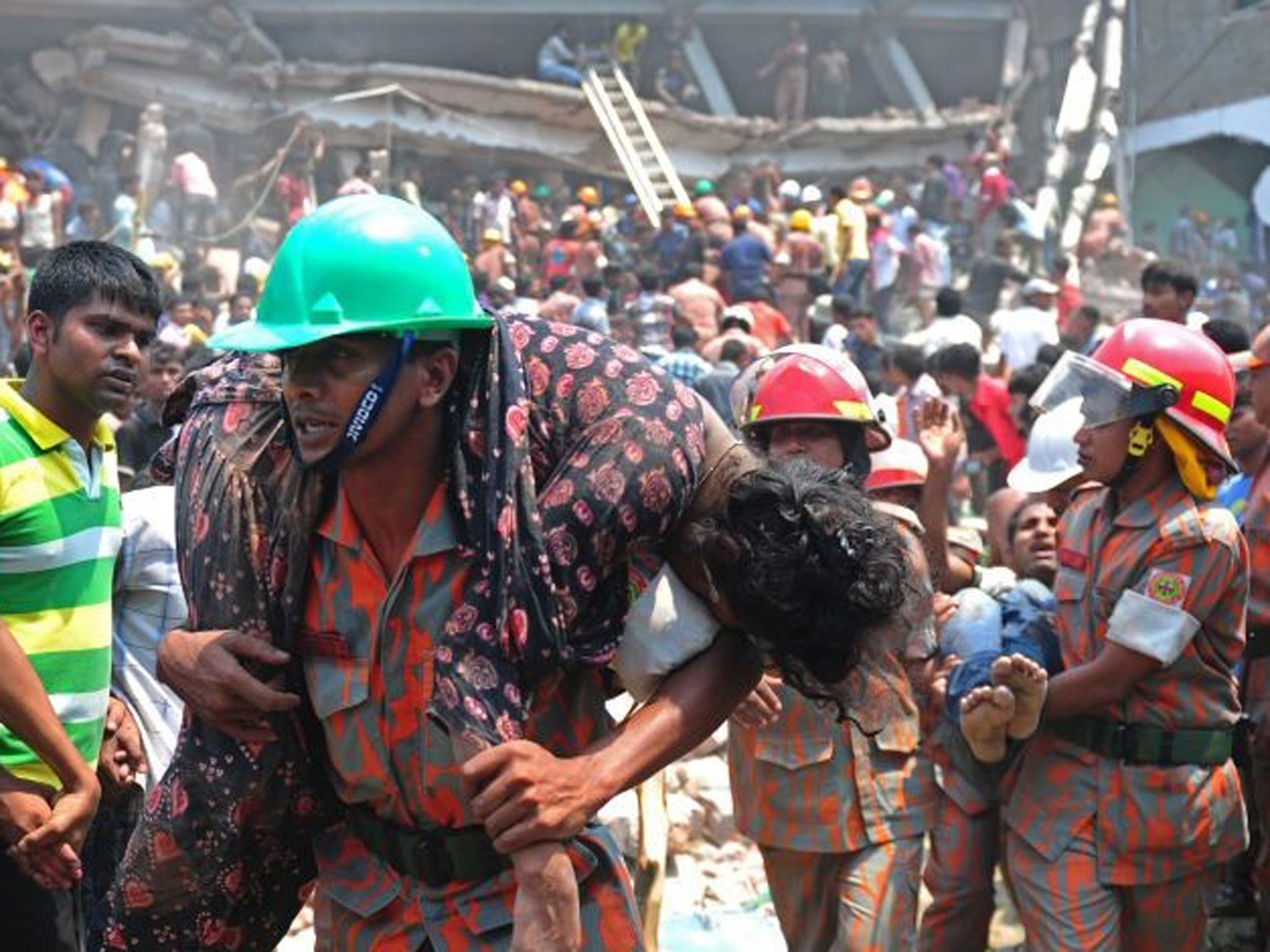 A Bangladeshi firefighter carries an injured garment worker after an eight-storey building collapsed in Savar, on the outskirts of Dhaka