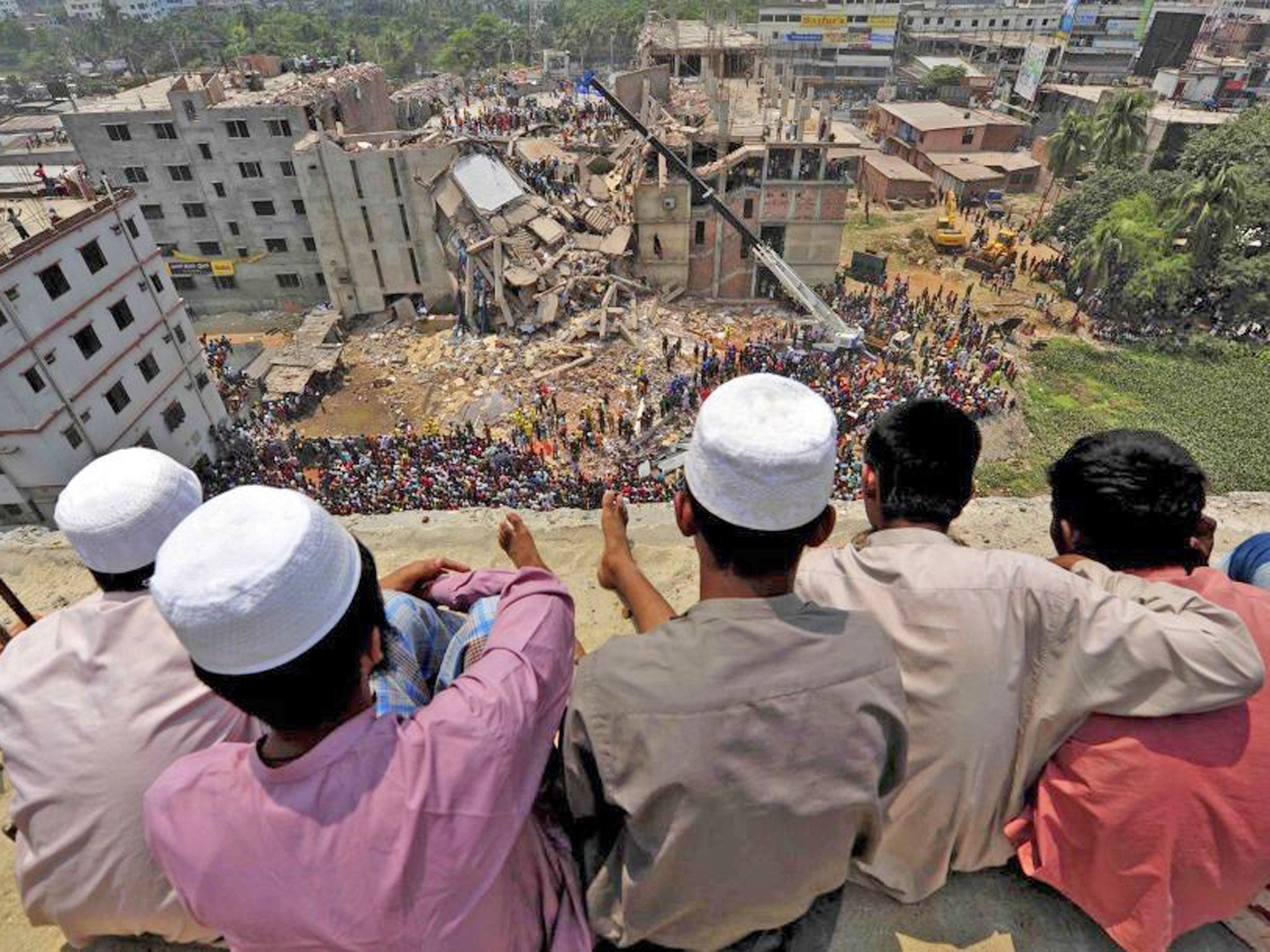 People watch as rescue workers continue their operations at the collapsed Rana Plaza building in Savar, outside Dhaka