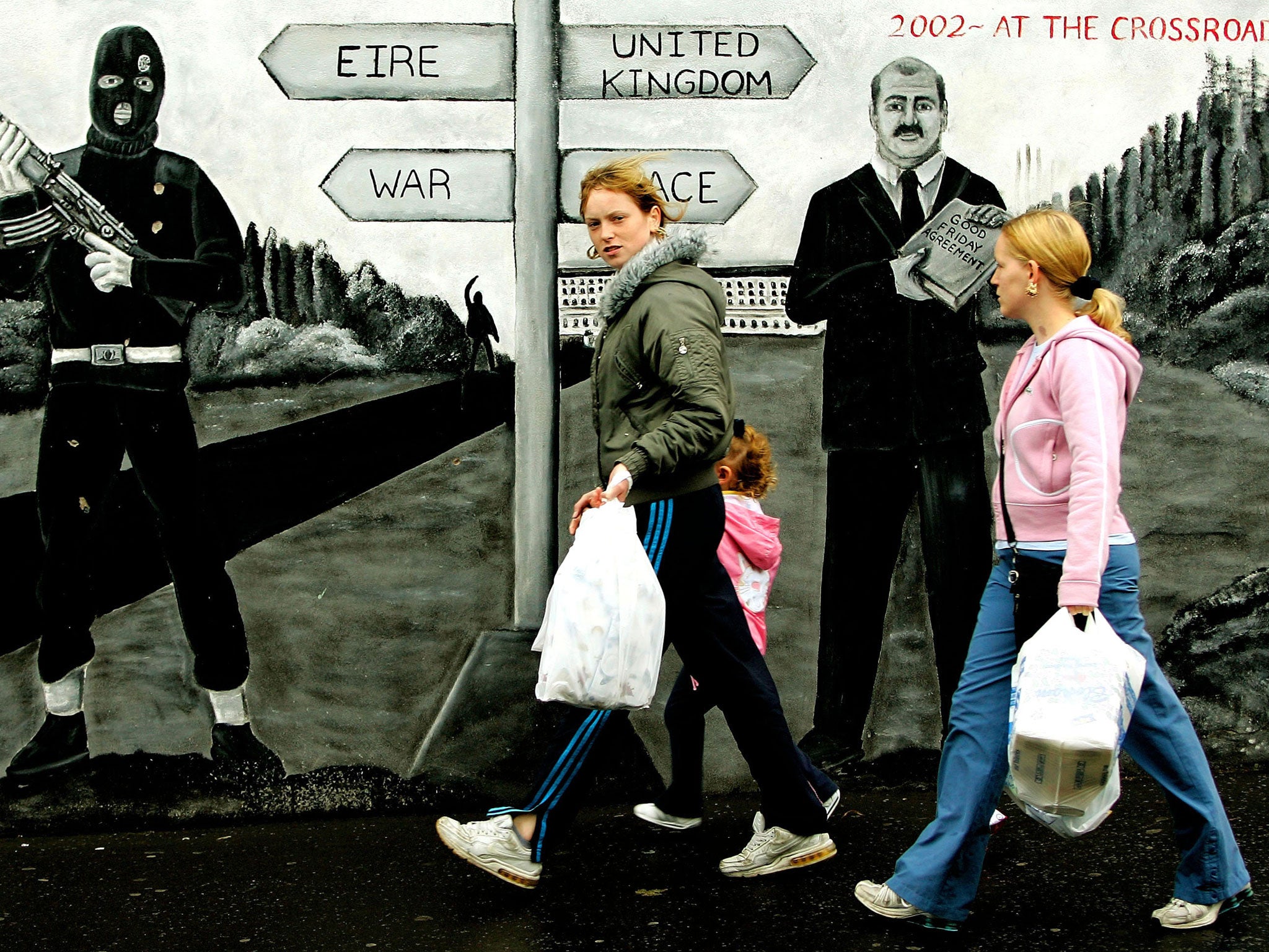Signs of the times: Shoppers pass by a pro-UVF mural in Belfast’s Shankill Road
