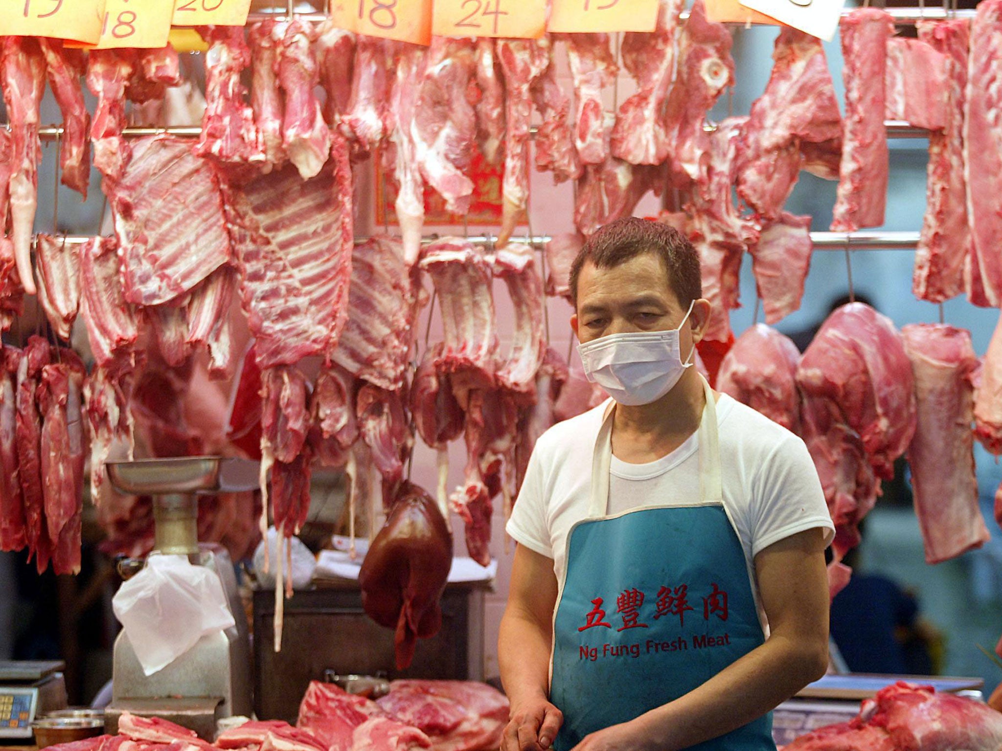 A butcher wears a mask on his market stall to protect against a killer outbreak of pneumonia in Hong Kong, 03 April 2003.