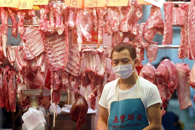 A butcher wears a mask on his market stall to protect against a killer outbreak of pneumonia in Hong Kong, 03 April 2003.