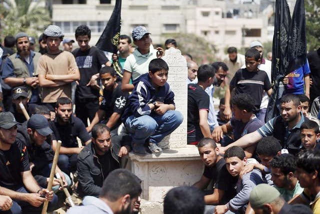 Palestinians sit around the grave of Haitham Mishal in Gaza City