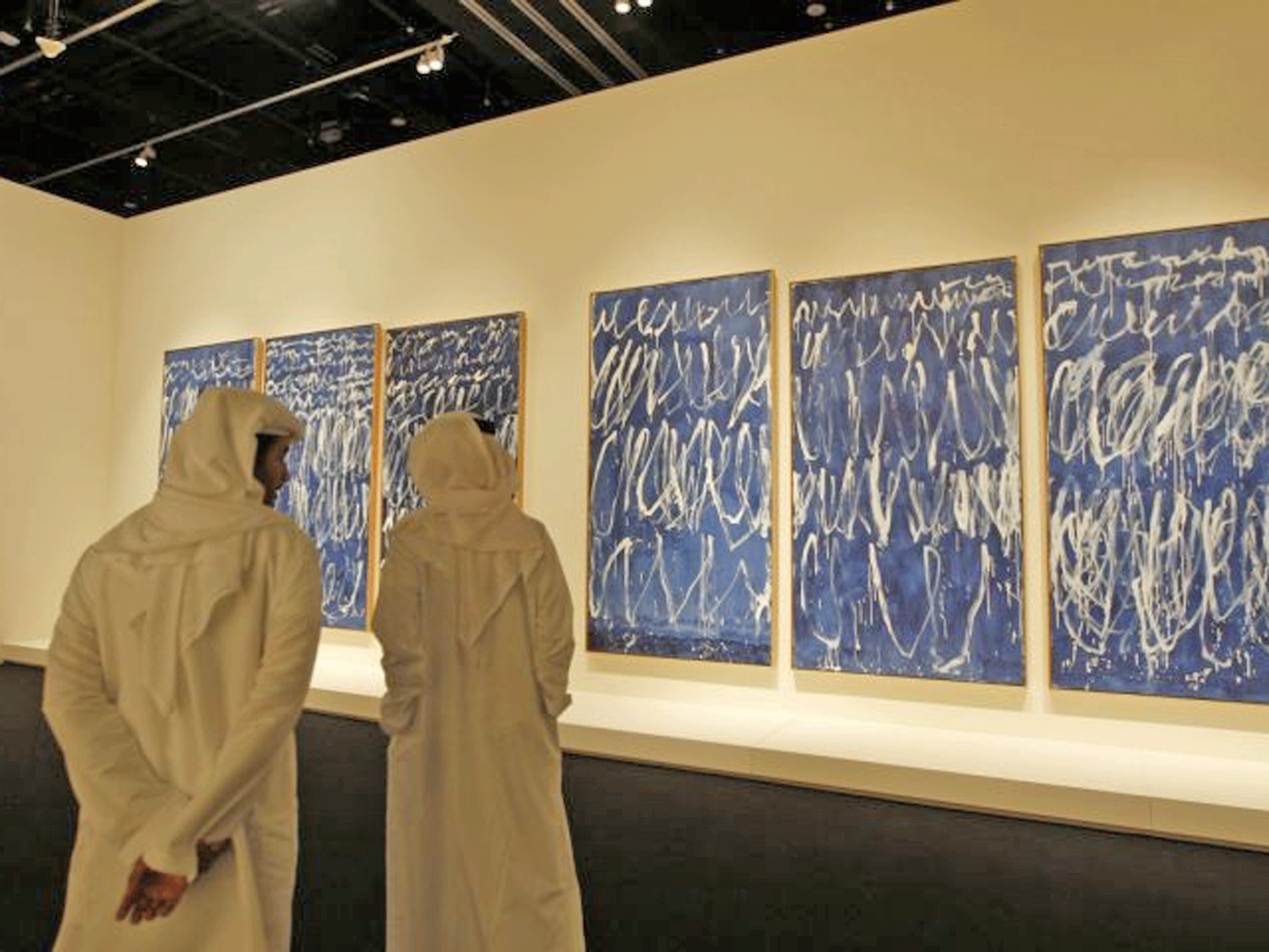 Emirati visitors look at 'Untitled I-IX' by American artist Cy Twombly during the opening of the 'Birth of a Museum' exhibition in Abu Dhabi