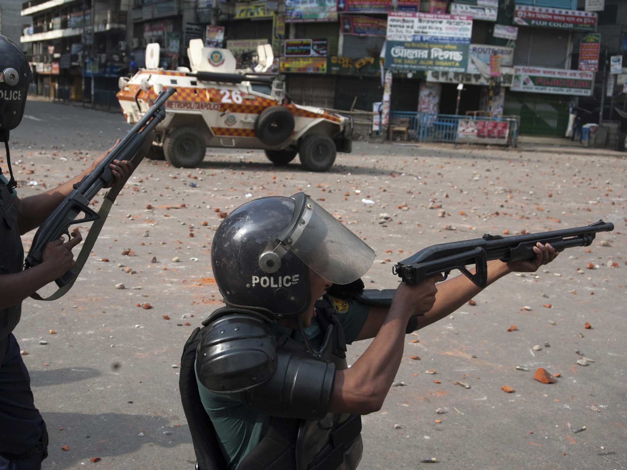 Policemen aim at protesters on a street in Dhaka