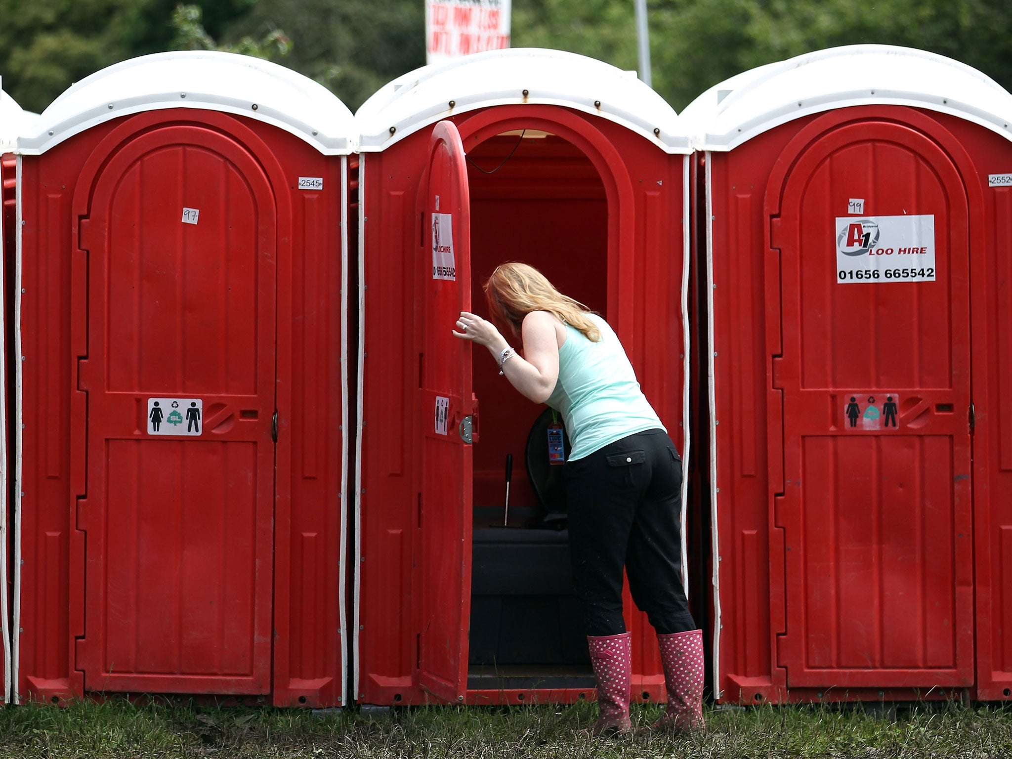 A woman checks the condition of a portable toilet at the Glastonbury Festival site at Worthy Farm, Pilton on June 22, 2011 in Glastonbury, England.